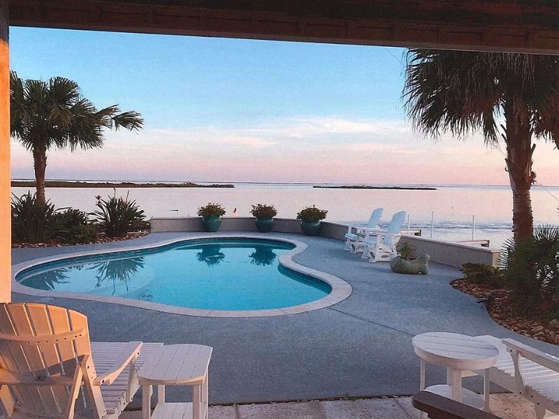 Outdoor pool framed by palm trees during sunset